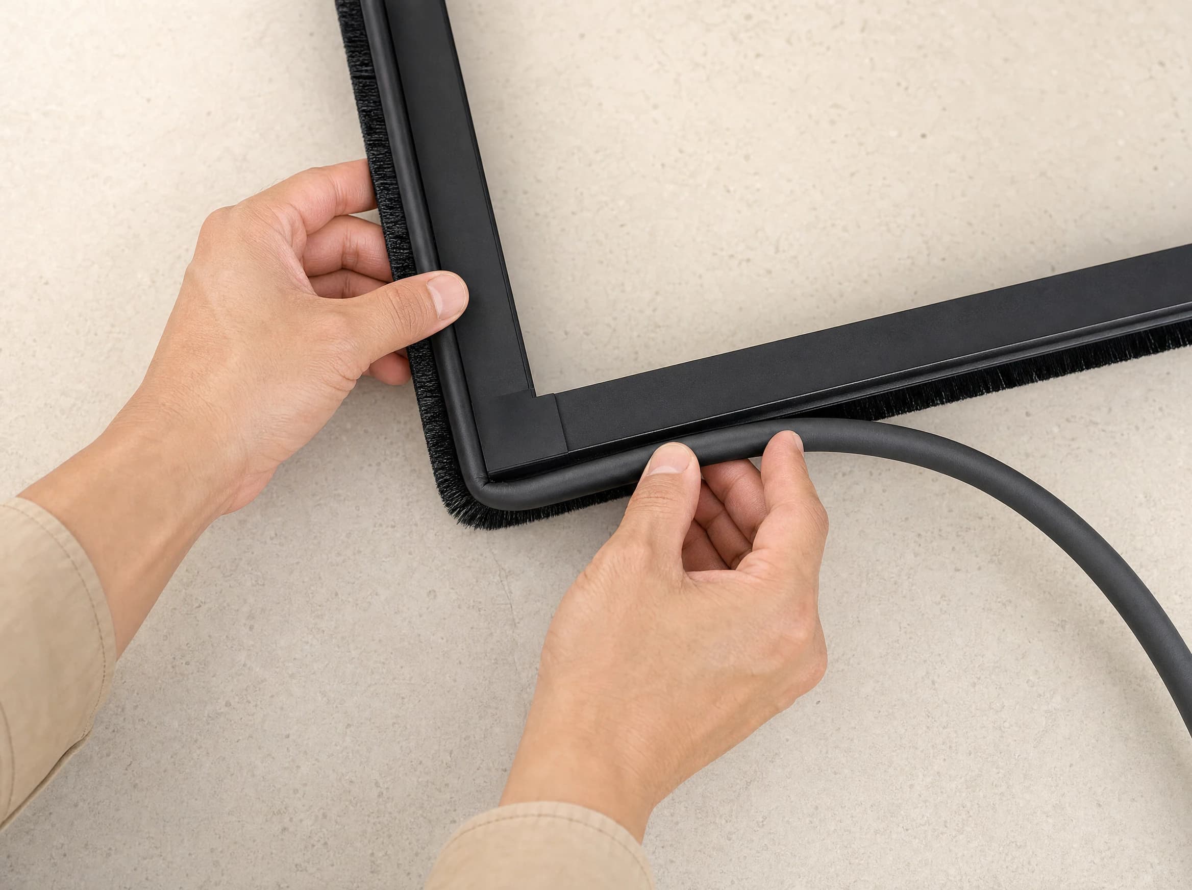 Hands fitting a compressible sealing strip around the OneRest blind frame