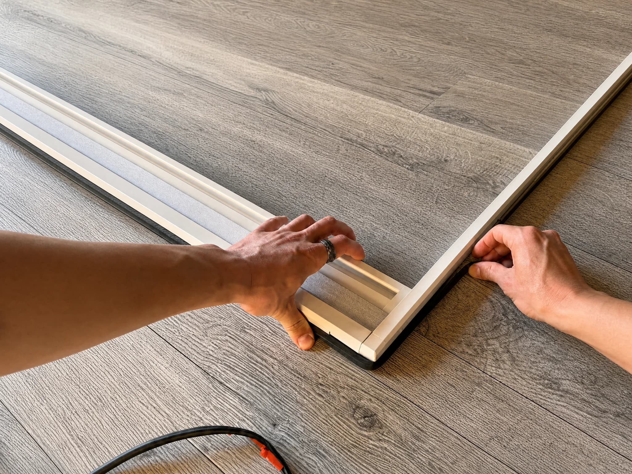 Hands fitting a compressible sealing strip around the OneRest blind frame