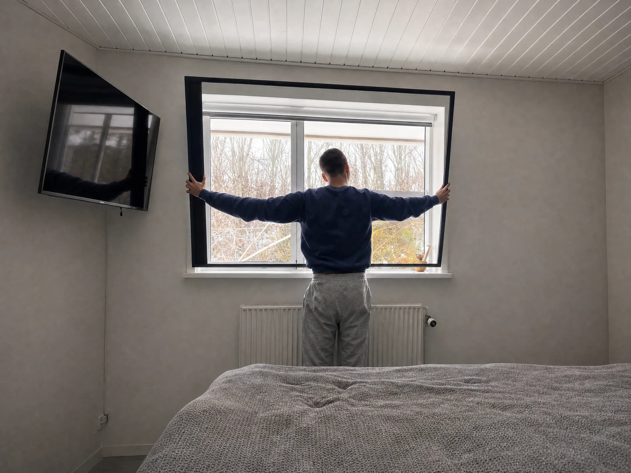 A person placing an assembled OneRest blackout blind inside a window recess
